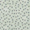 A repeating pattern of small white birds with dark gray bodies and dark blue flowers on a pale mint green cotton fabric with subtle white polka dots.