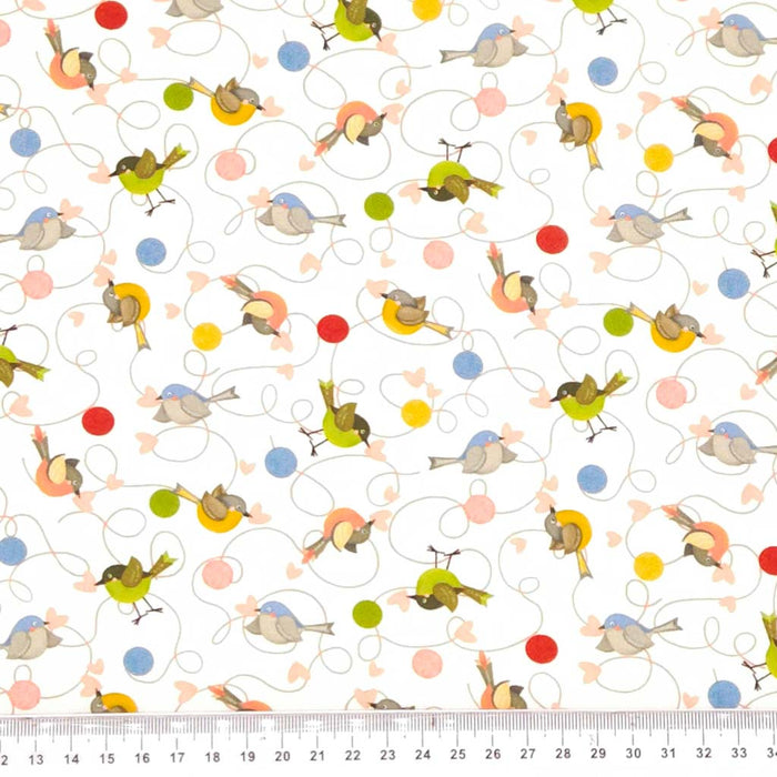 Patterned fabric with colorful birds and circles on a white cotton fabric, ruler at the bottom for scale.