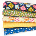 Stack of colorful fabric fat quarters with various patterns on cotton fabric