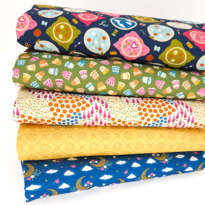 Stack of colorful fabric fat quarters with various patterns on cotton fabric