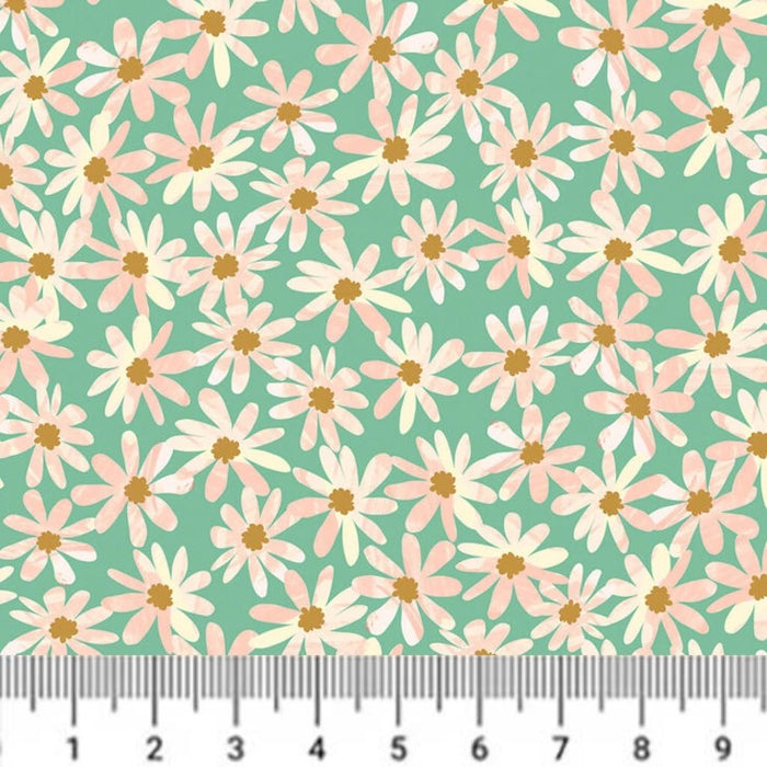 Pattern of pink and white flowers with yellow centers on a green cotton quilting fabric, measured by a ruler.
