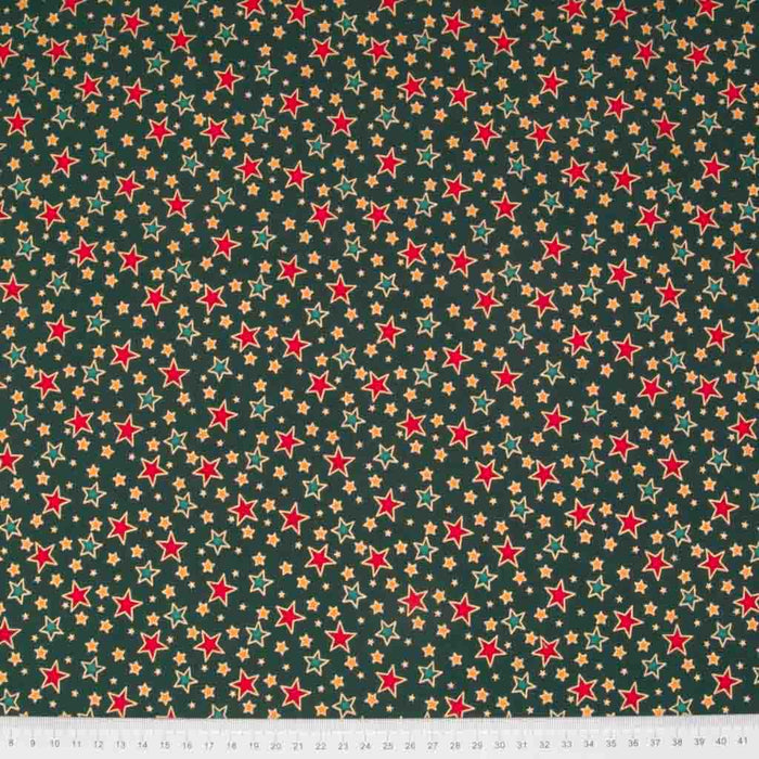 Red and green stars printed on a green cotton christmas fabric with a ruler