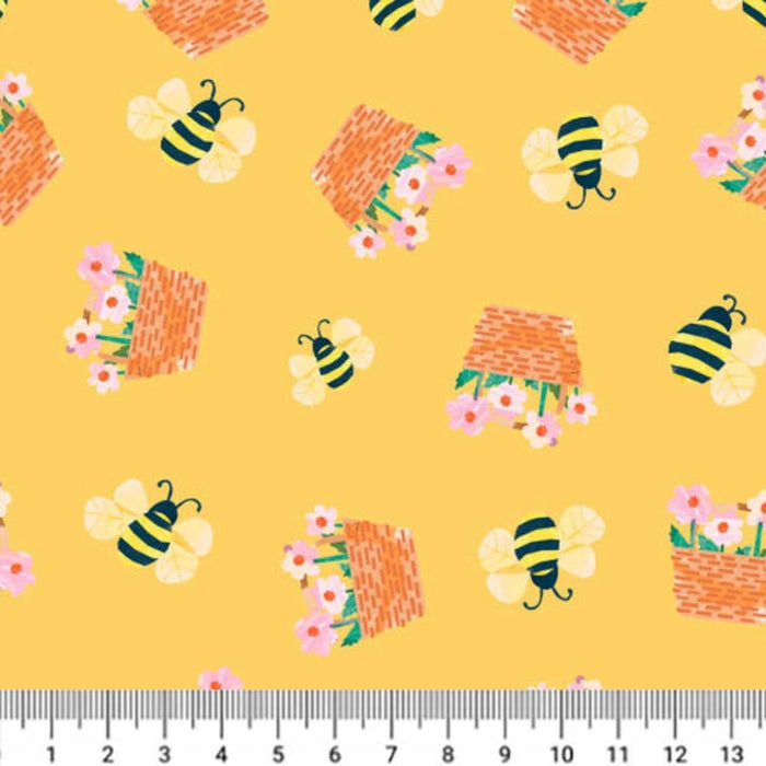 Fabric with bees, beehives, and flowers on a yellow cotton quilting fabric