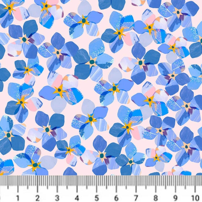 Pattern of blue flowers with a ruler at the bottom for scale on a pink cotton quilting fabric