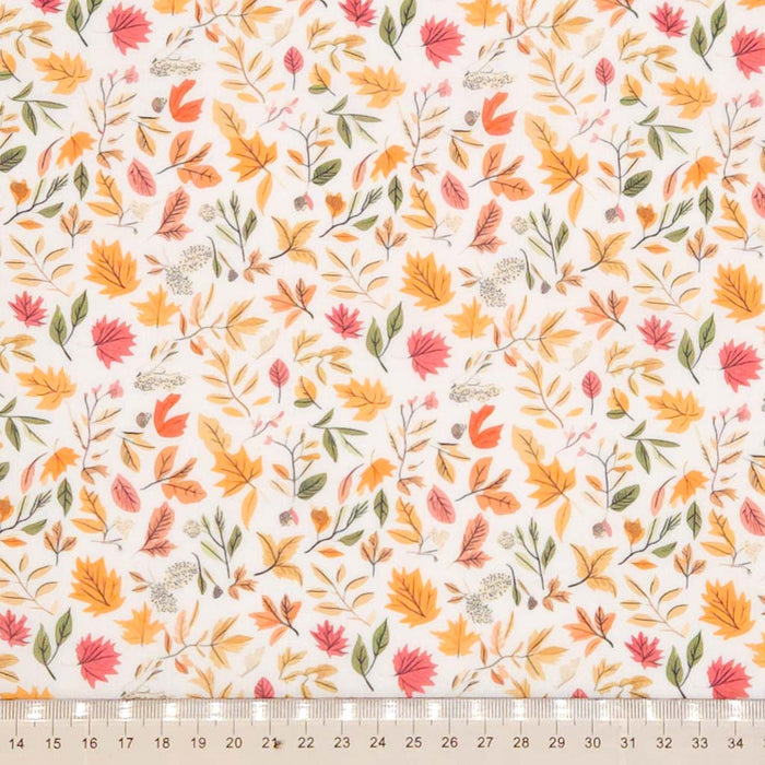 Pattern of autumn leaves and branches on a white polycotton fabric with a cm ruler
