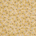 A repeating pattern of small white daisy-like flowers with dark stems on a warm tan cotton quilting fabric, interspersed with green dots and repeated diagonal text reading 'friends'.