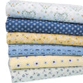 A stack of six fat quarters of fabric with various floral and insect patterns in pastel colors, including blue, yellow, and light green, on a white background.