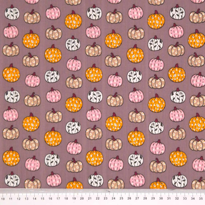 Ditsy decorated pumpkins printed on a grey polycotton fabric with a cm ruler