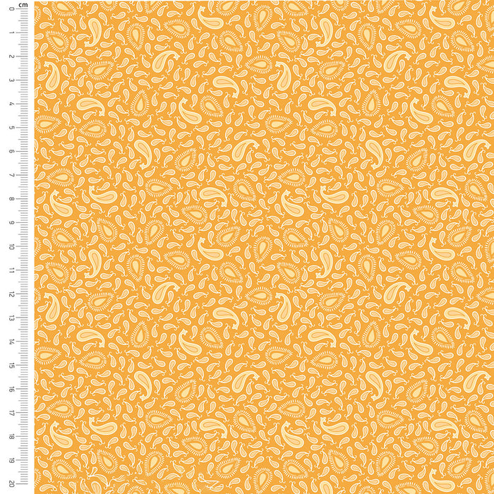 Fabric with a pattern of small white shapes on an orange background, accompanied by a ruler for scale.