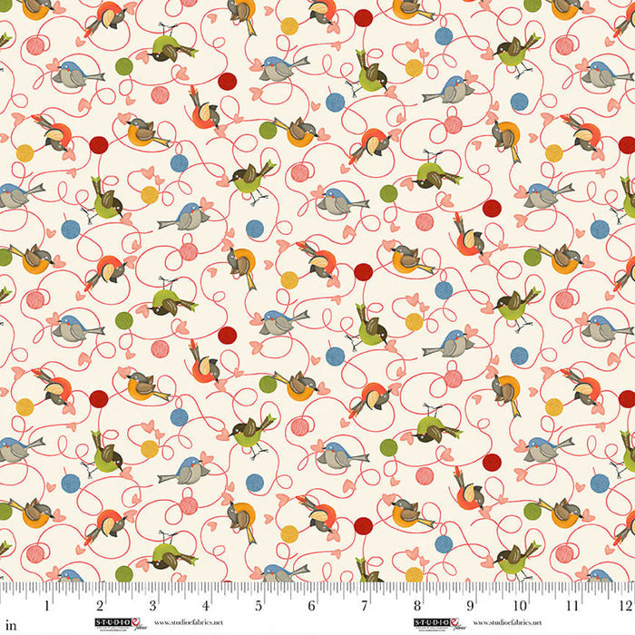Patterned fabric with birds and ballsof wool on a white background, featuring a ruler at the bottom.