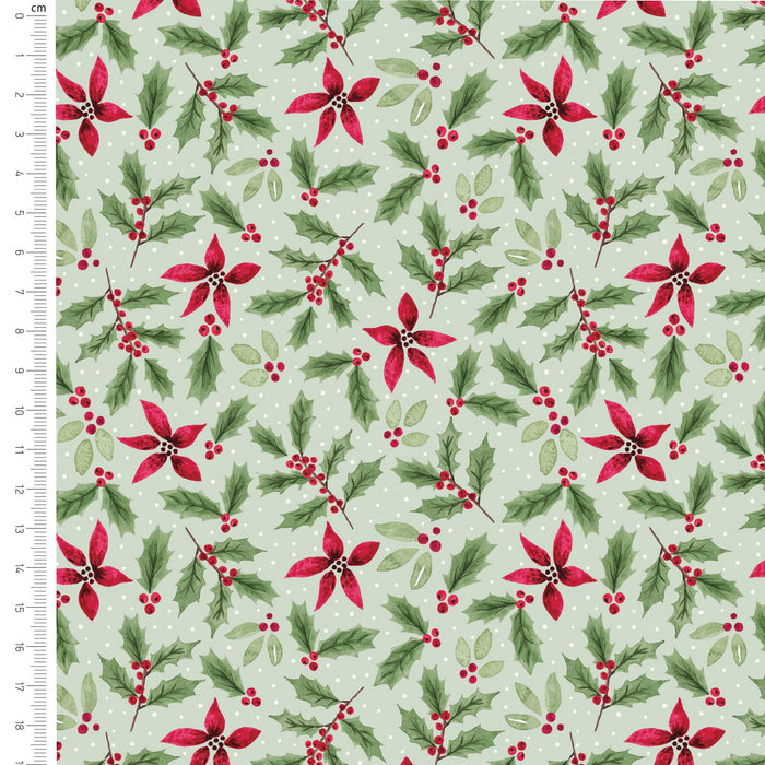 A repeating Christmas pattern on fabric or paper showing red poinsettias, green holly leaves, and small red berry clusters on a pale mint green background with white polka dots. A ruler in centimeters appears along the left edge for scale.