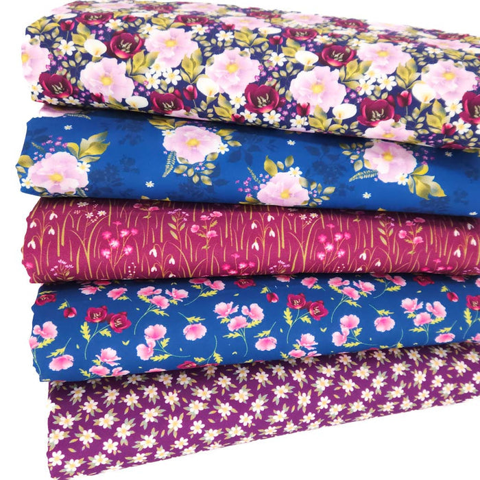 Stack of floral fabric fat quarters in various purple and blue shades on a white background