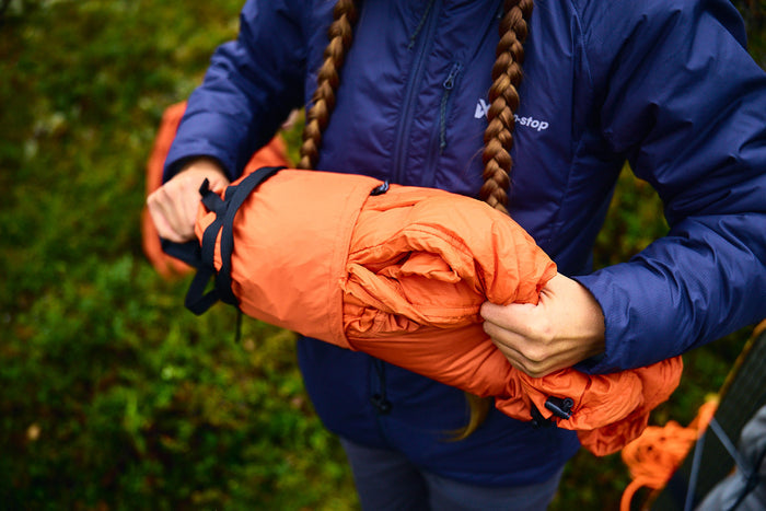 Lifestyle image of the Bivvy Bag, a person holds the bag while wearing a Non-stop branded blue coat.