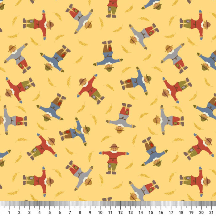 Pattern of scarecrows on a yellow cotton quilting fabric with a ruler at the bottom.
