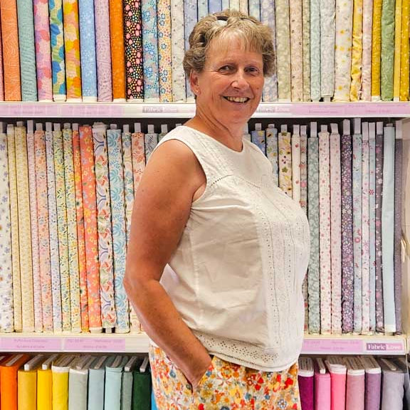 Woman standing in front of a colorful array of fabric swatches