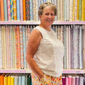 Woman standing in front of a colorful array of fabric swatches
