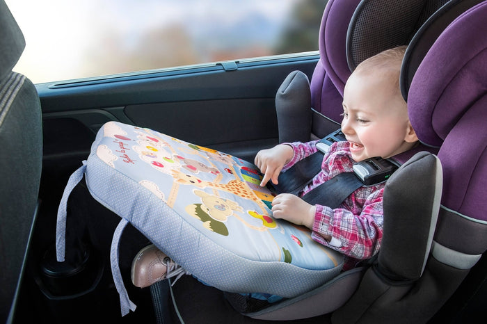 Baby in the car smiling while playing with Sophie la Girafe Touch & Play Board on his lap