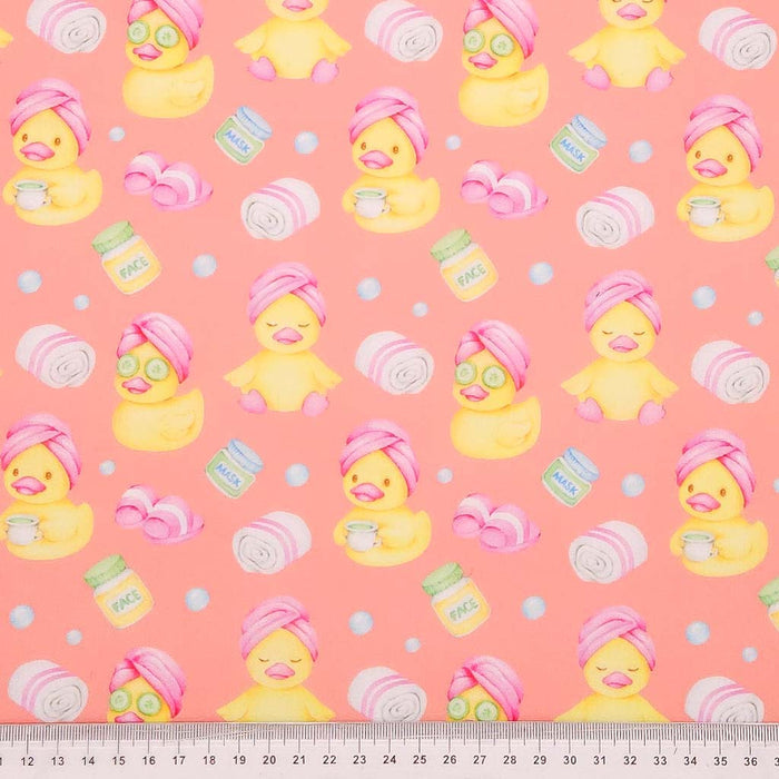 Rubber ducks on a coral polycotton fabric with a cm ruler