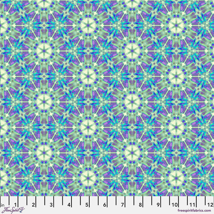 A geometric pattern in purples and greens printed on a cotton quilting fabric with a cm ruler