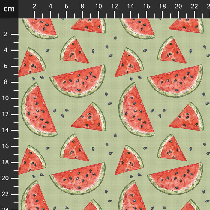 Pattern of watermelon slices on a light green cotton quilting fabric with a ruler for scale.